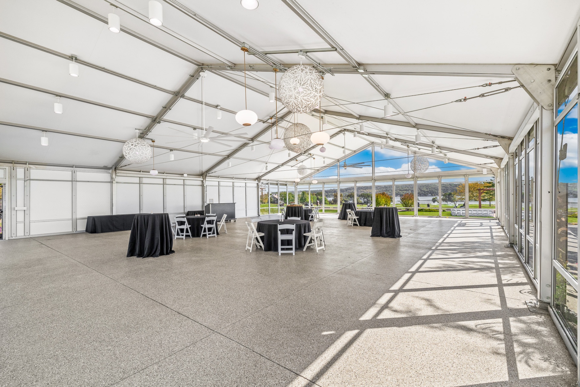 Light-filled white event tent with cocktail tables and lake views