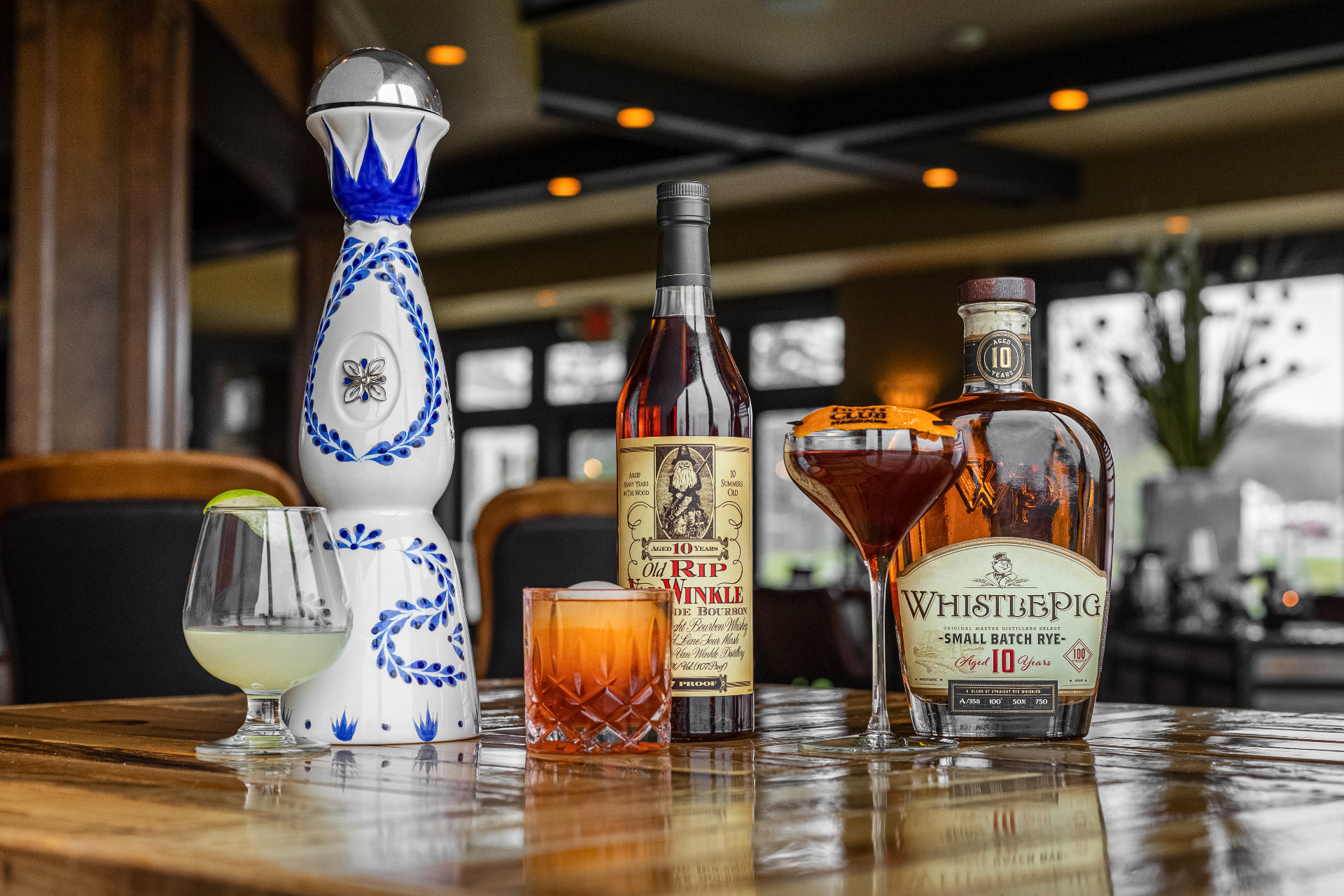 Premium tequila, bourbon and rye bottles with cocktails arranged on the bar