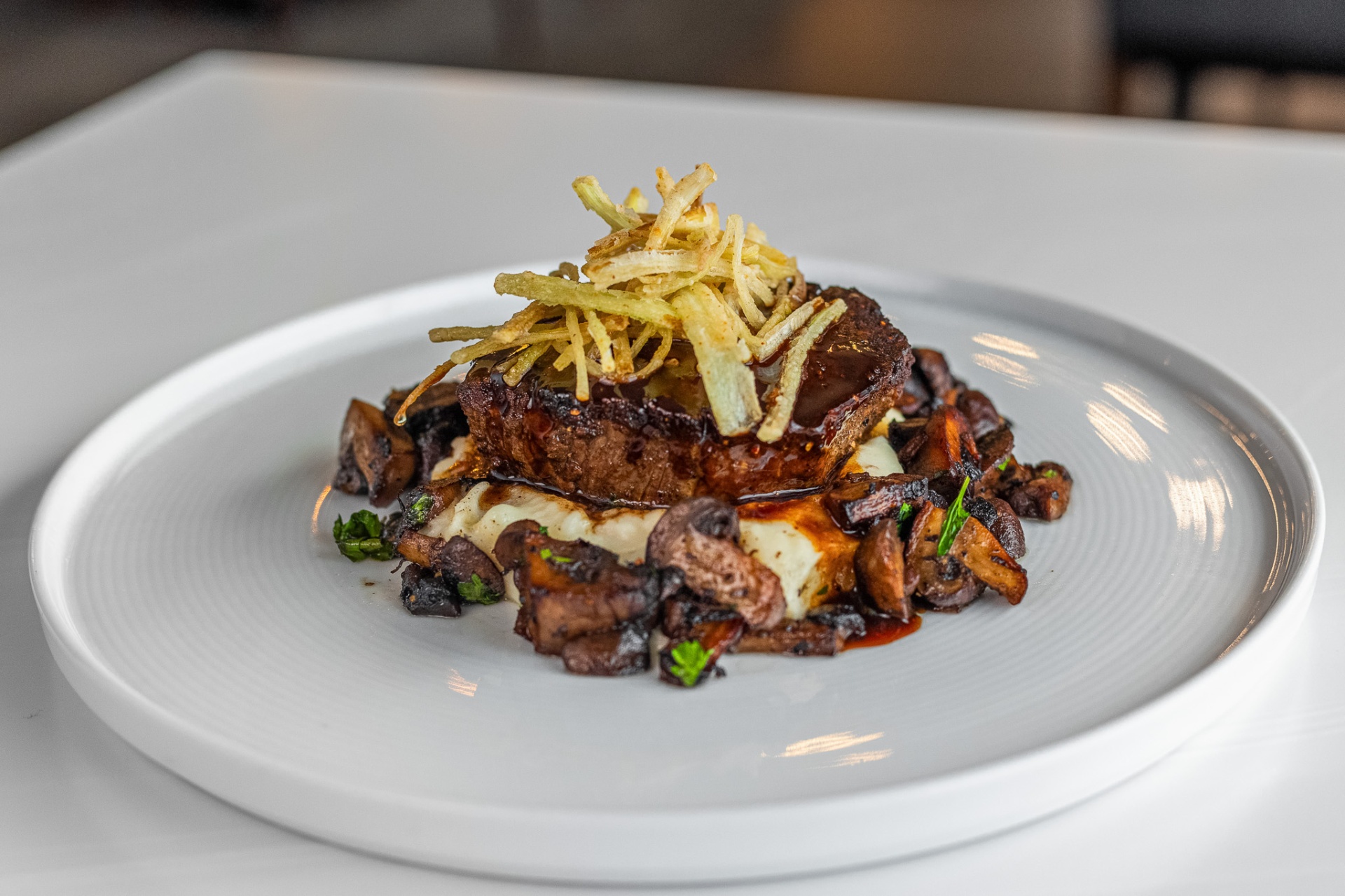 Seared filet mignon over whipped potatoes with mushrooms and crispy shoestring potatoes