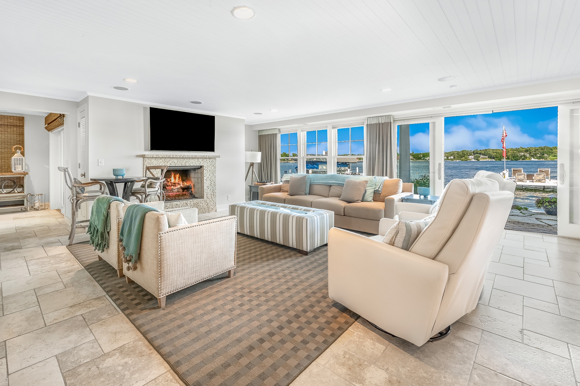 Lakefront living room with fireplace and floor-to-ceiling views of the water
