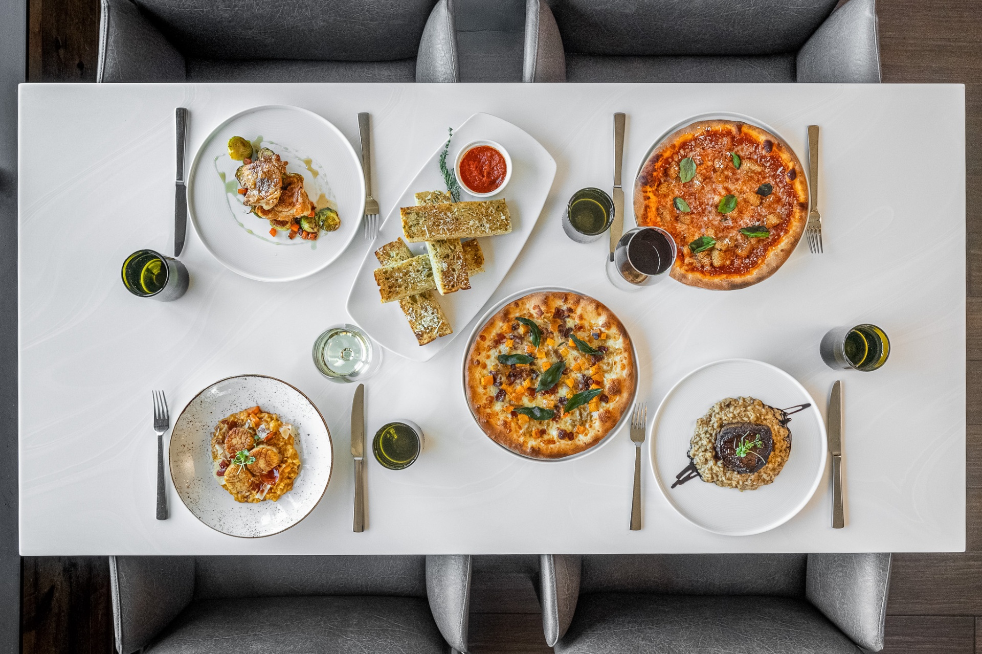 Overhead spread of pizzas, risotto, scallops and garlic bread on a long table
